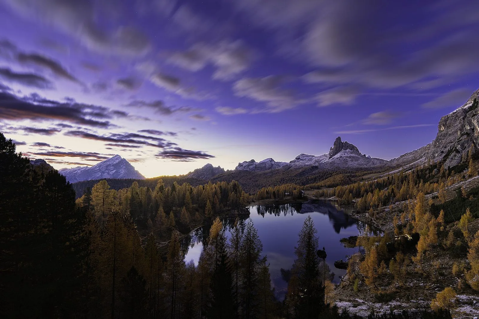 Il Lago Federa al crepuscolo tra i larici dorati d'autunno, con il Becco di Mezzodì e l'Antelao innevati sullo sfondo